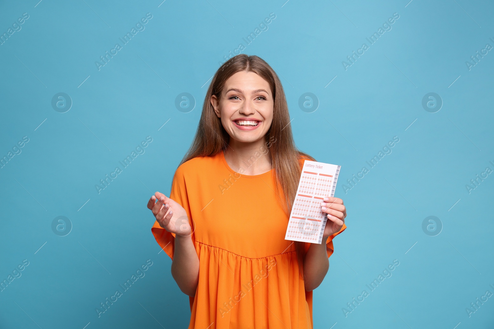 Photo of Portrait of happy young woman with lottery ticket on light blue background