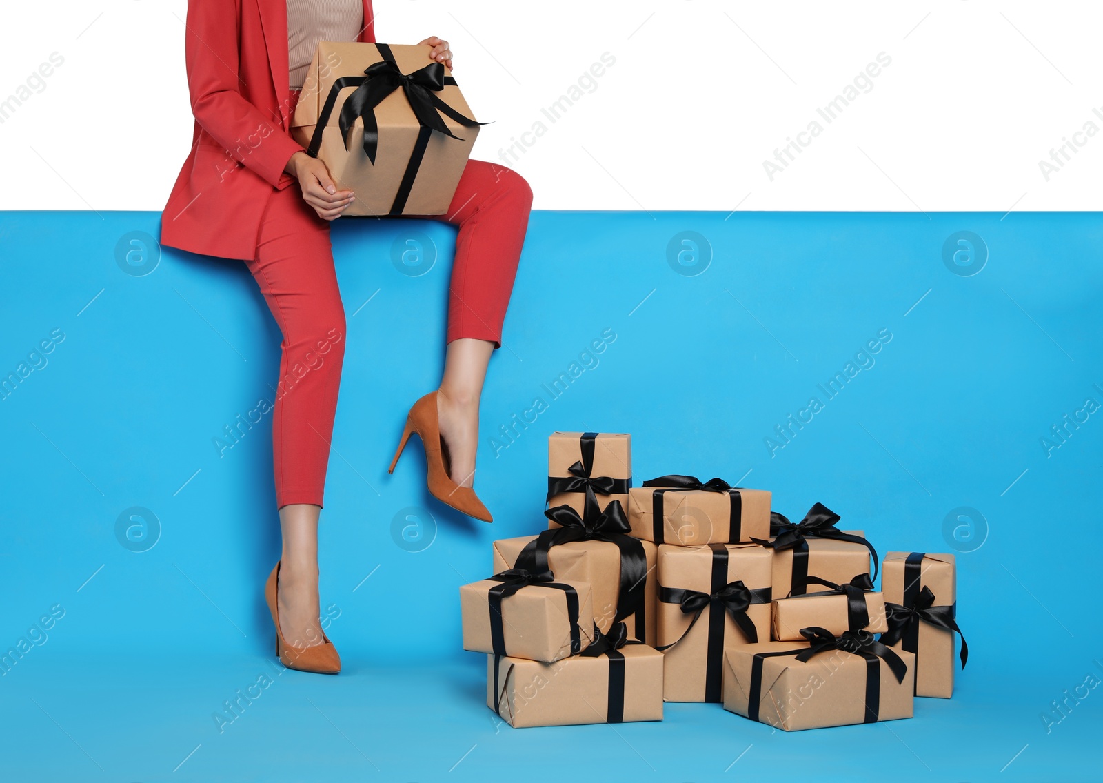 Photo of Woman and gift boxes on light blue background, closeup. Black Friday