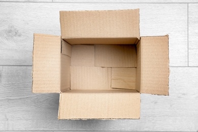 Photo of Open empty cardboard box on wooden floor