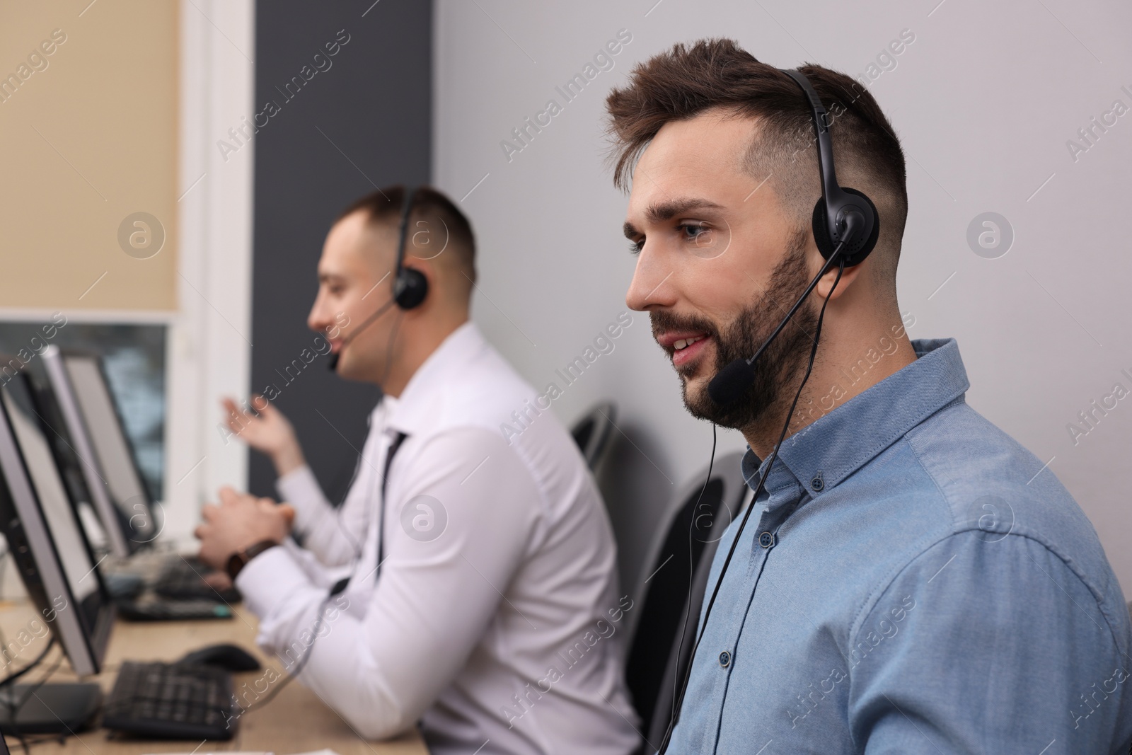 Photo of Call center operators with headsets working in modern office