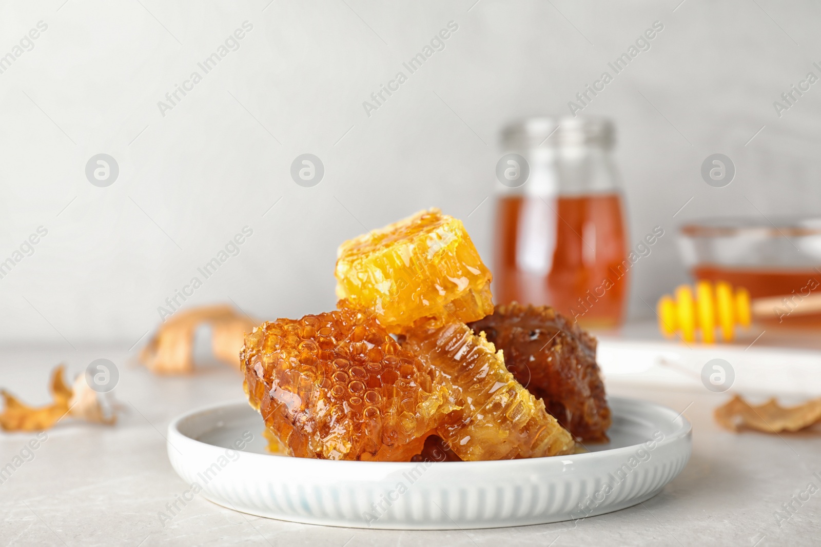 Photo of Plate with fresh tasty honeycombs on gray table