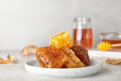 Plate with fresh tasty honeycombs on gray table