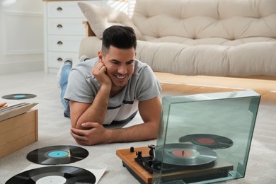 Photo of Man listening to music with turntable while lying on floor at home