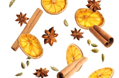 Slices of dried orange, aromatic anise stars, cinnamon and cardamom falling on white background