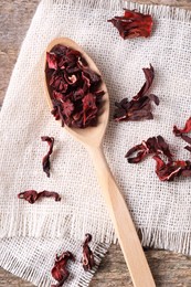 Spoon with dry hibiscus tea on table, flat lay