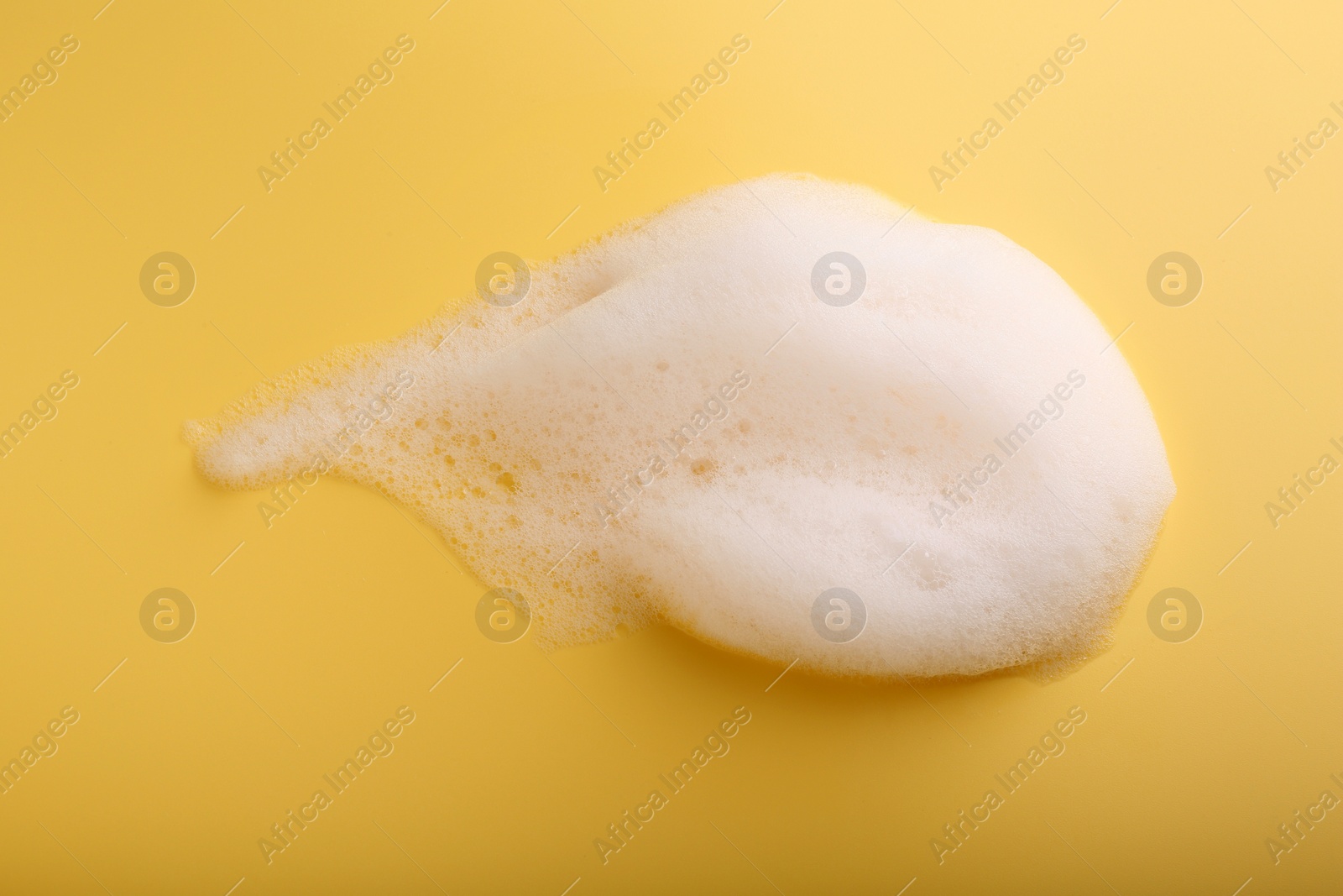 Photo of Sample of fluffy foam on yellow background, top view