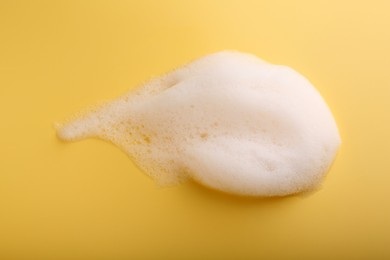 Photo of Sample of fluffy foam on yellow background, top view