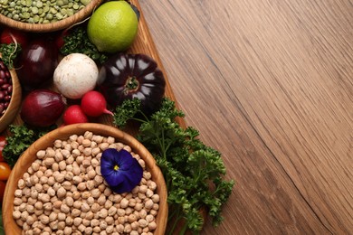 Photo of Different vegetables on wooden table, flat lay and space for text. Vegan diet