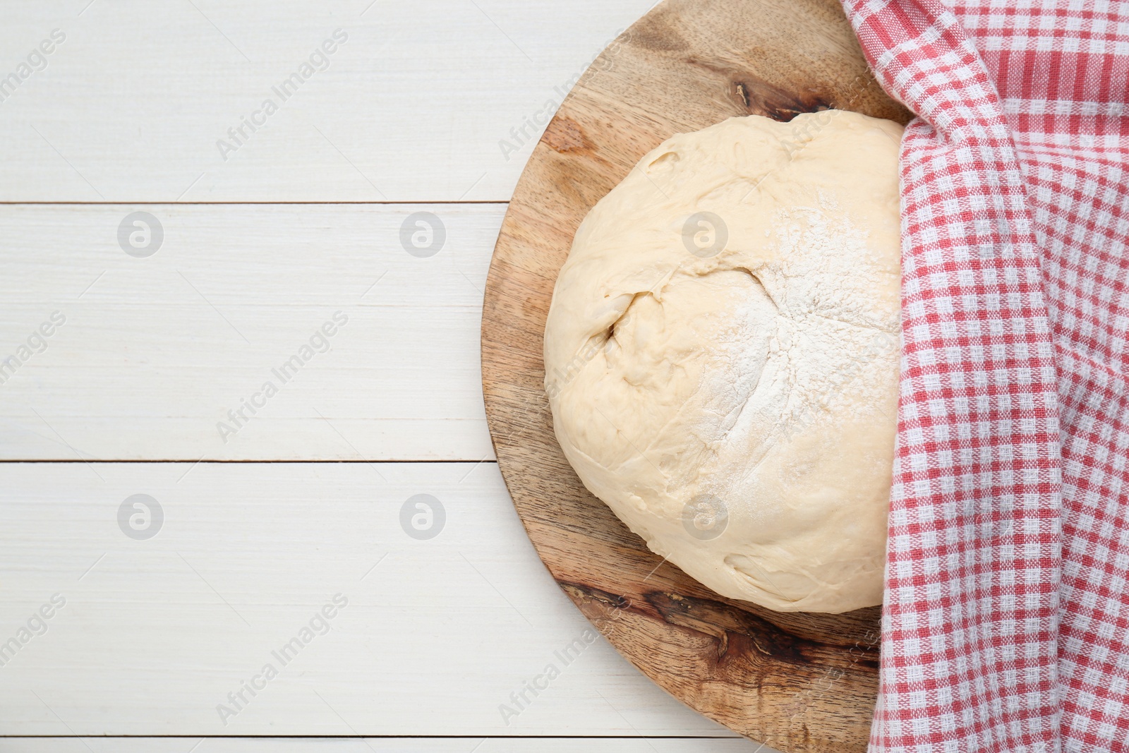 Photo of Fresh yeast dough with flour on white wooden table, top view. Space for text