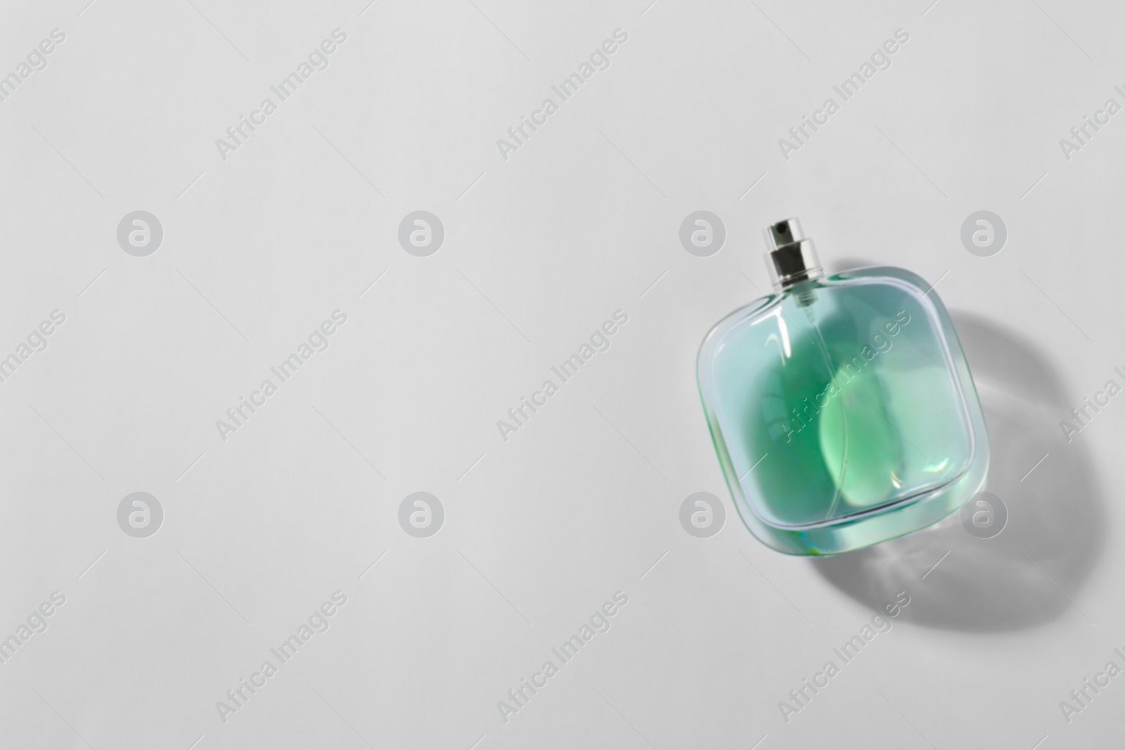 Photo of Bottle of perfume on light background, top view