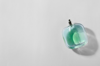 Bottle of perfume on light background, top view