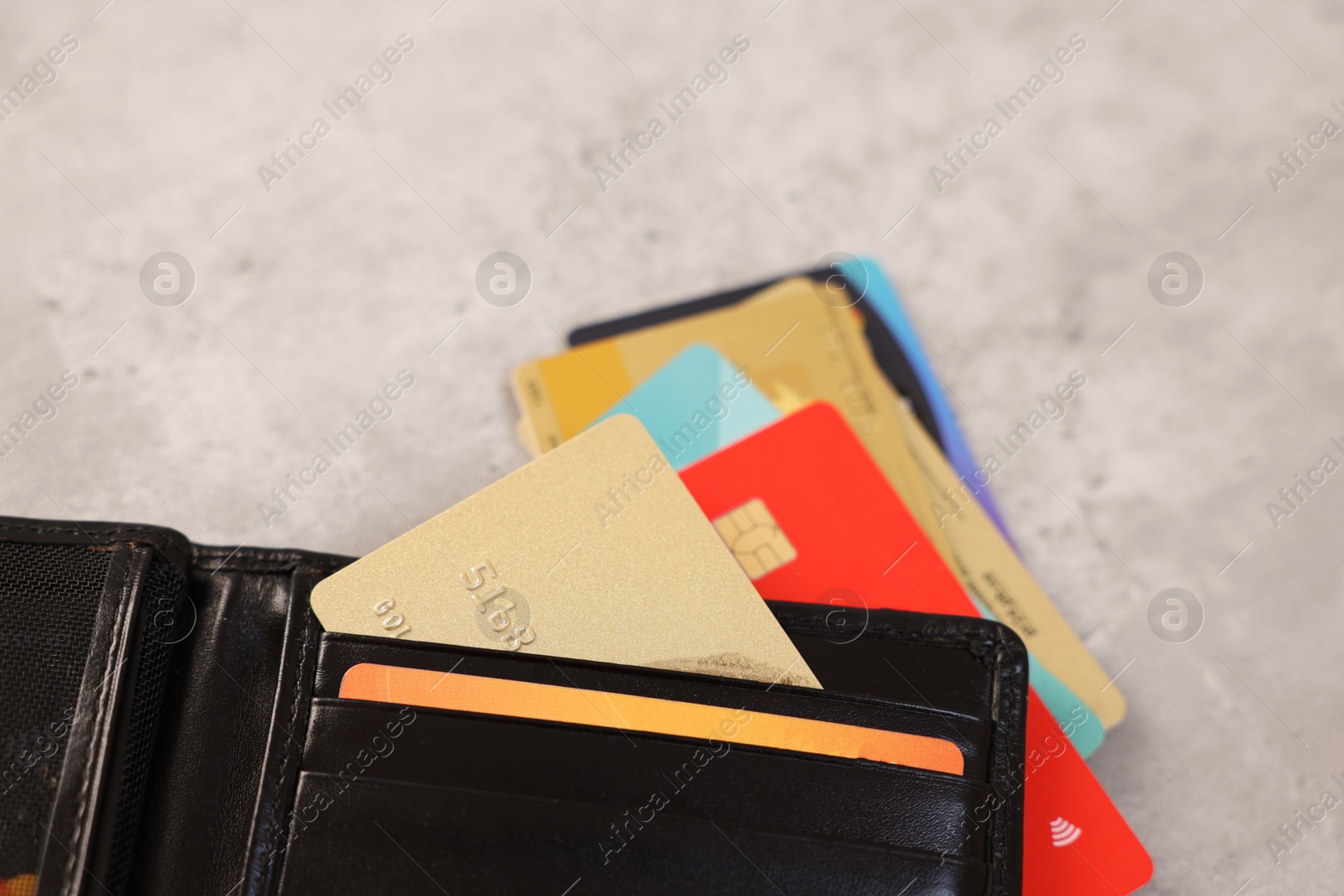 Photo of Many different credit cards and leather wallet on grey table, closeup