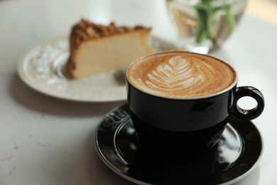 Photo of Cup of fresh coffee and dessert on white table, closeup