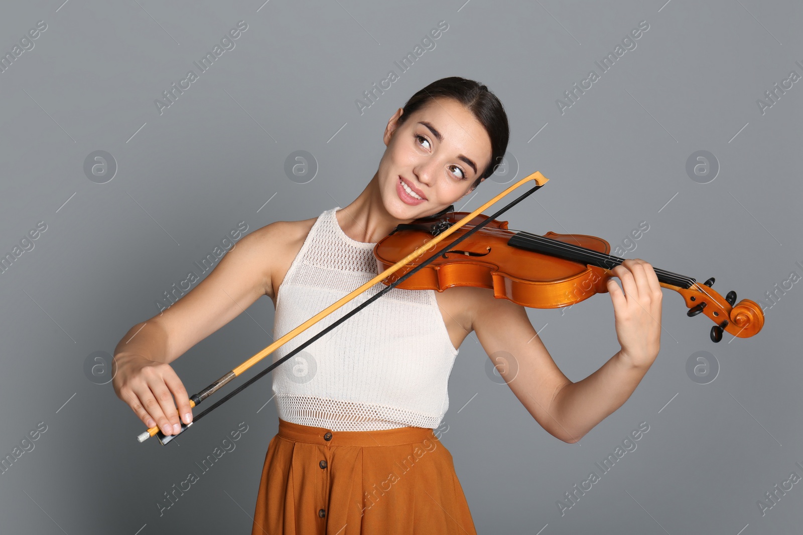 Photo of Beautiful woman playing violin on grey background