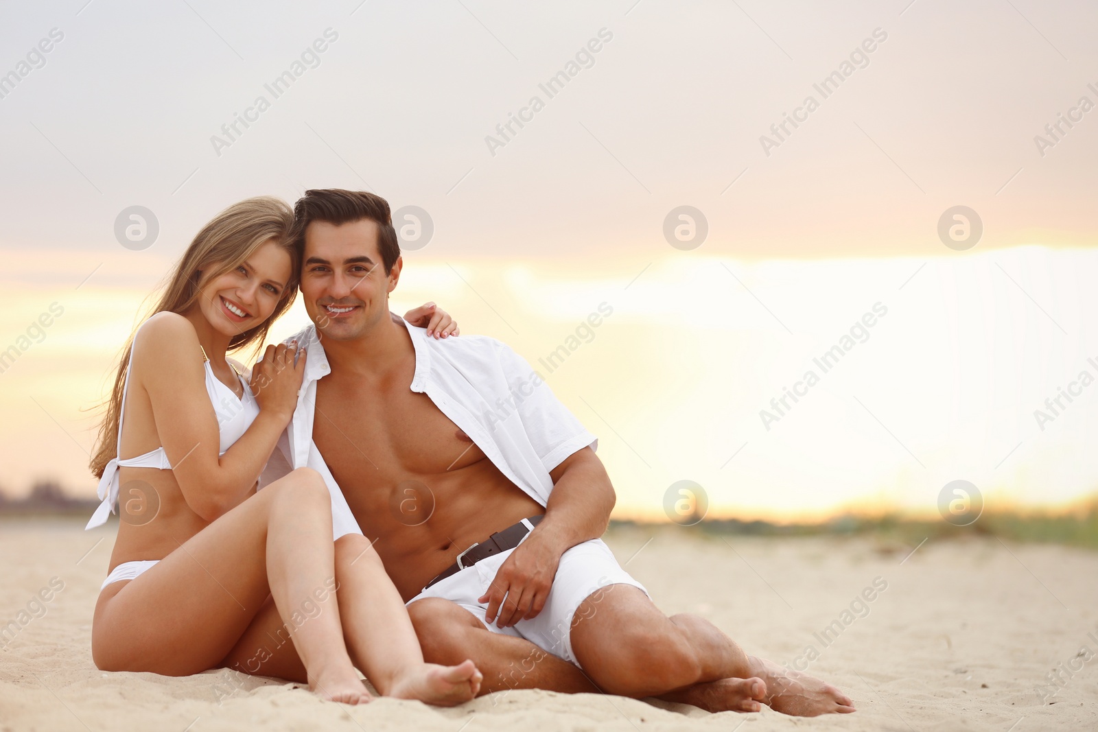 Photo of Happy young couple relaxing together on sea beach at sunset