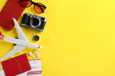 Flat lay composition with toy airplane and travel items on yellow background. Space for text