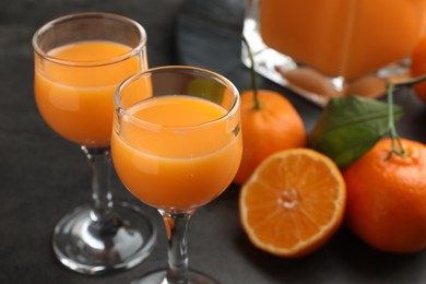 Photo of Delicious tangerine liqueur and fresh fruits on grey table, closeup