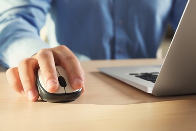 Man using computer mouse with laptop at table, closeup