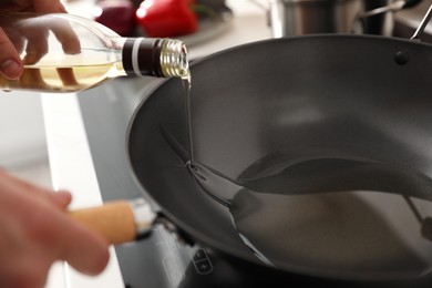 Man pouring cooking oil into frying pan in kitchen, closeup