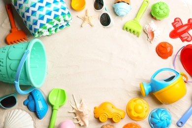 Photo of Flat lay composition with colorful beach toys on sand. Space for text