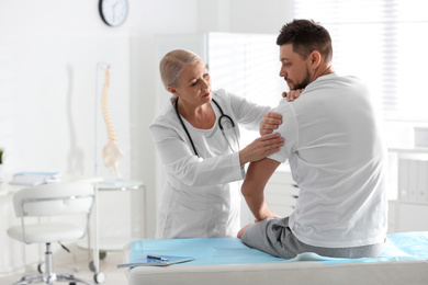 Male orthopedist examining patient's arm in clinic