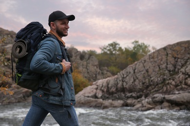 Photo of Man with backpack crossing mountain river on autumn day