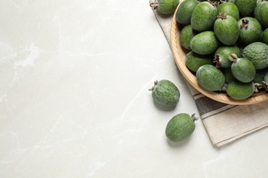 Flat lay composition with fresh green feijoa fruits on light grey marble table, space for text