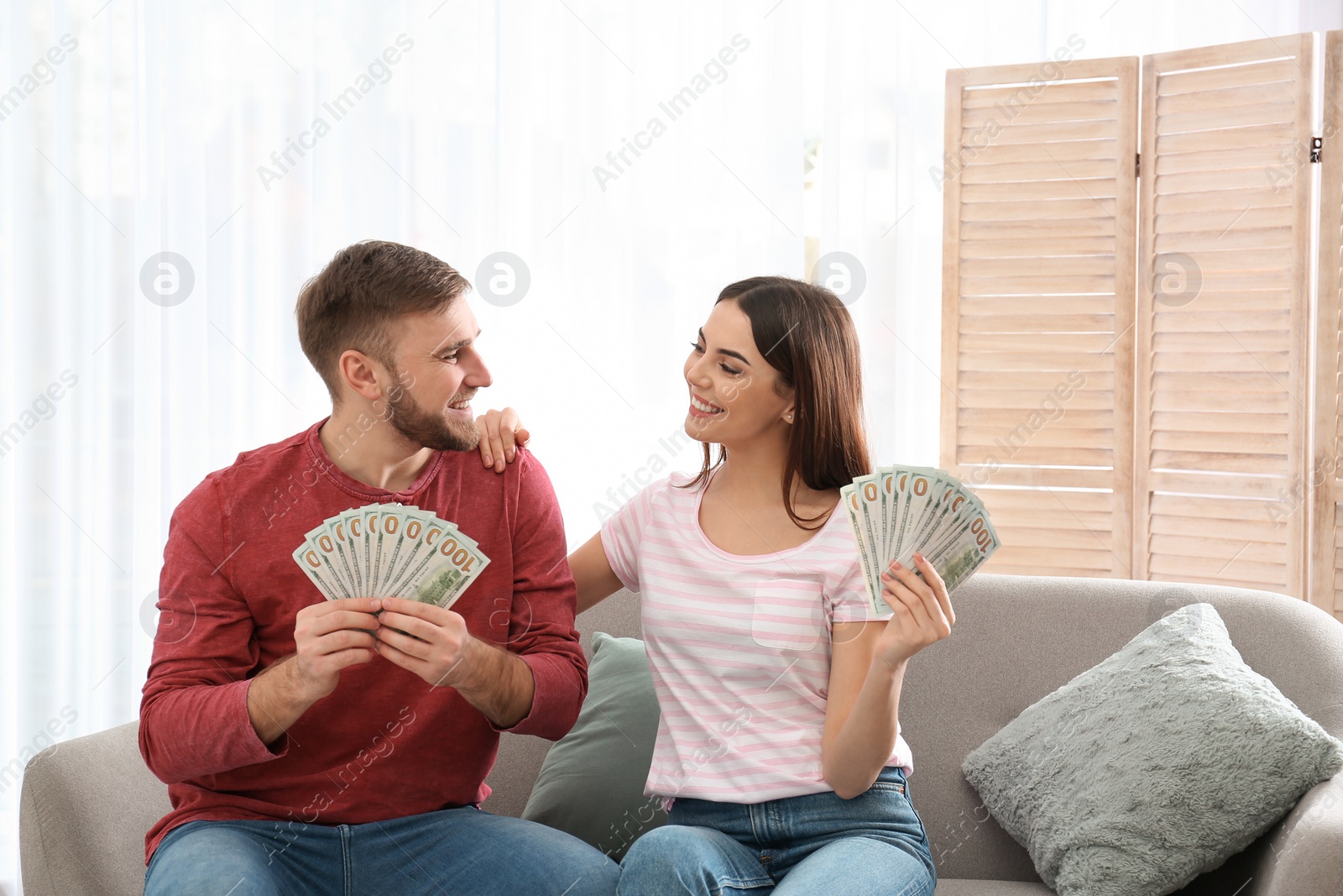 Photo of Beautiful young couple with money at home