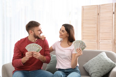 Beautiful young couple with money at home