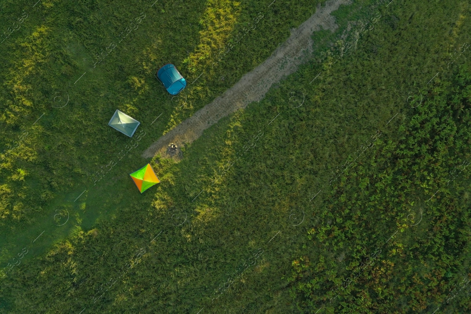 Photo of Aerial view of camping tents and bonfire on green meadow