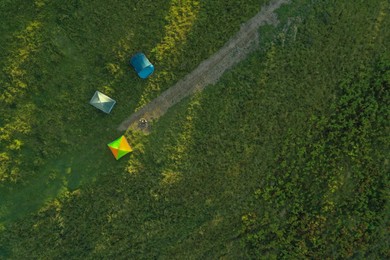 Aerial view of camping tents and bonfire on green meadow