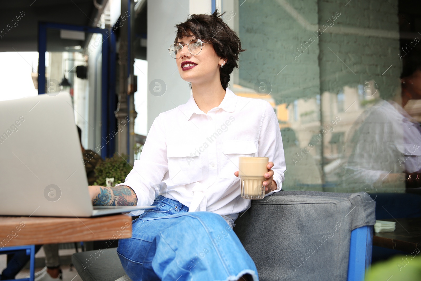 Photo of Young woman working with laptop at desk in cafe