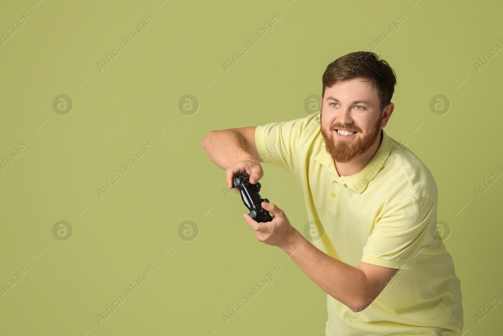 Photo of Happy man playing video game with controller on pale green background. Space for text