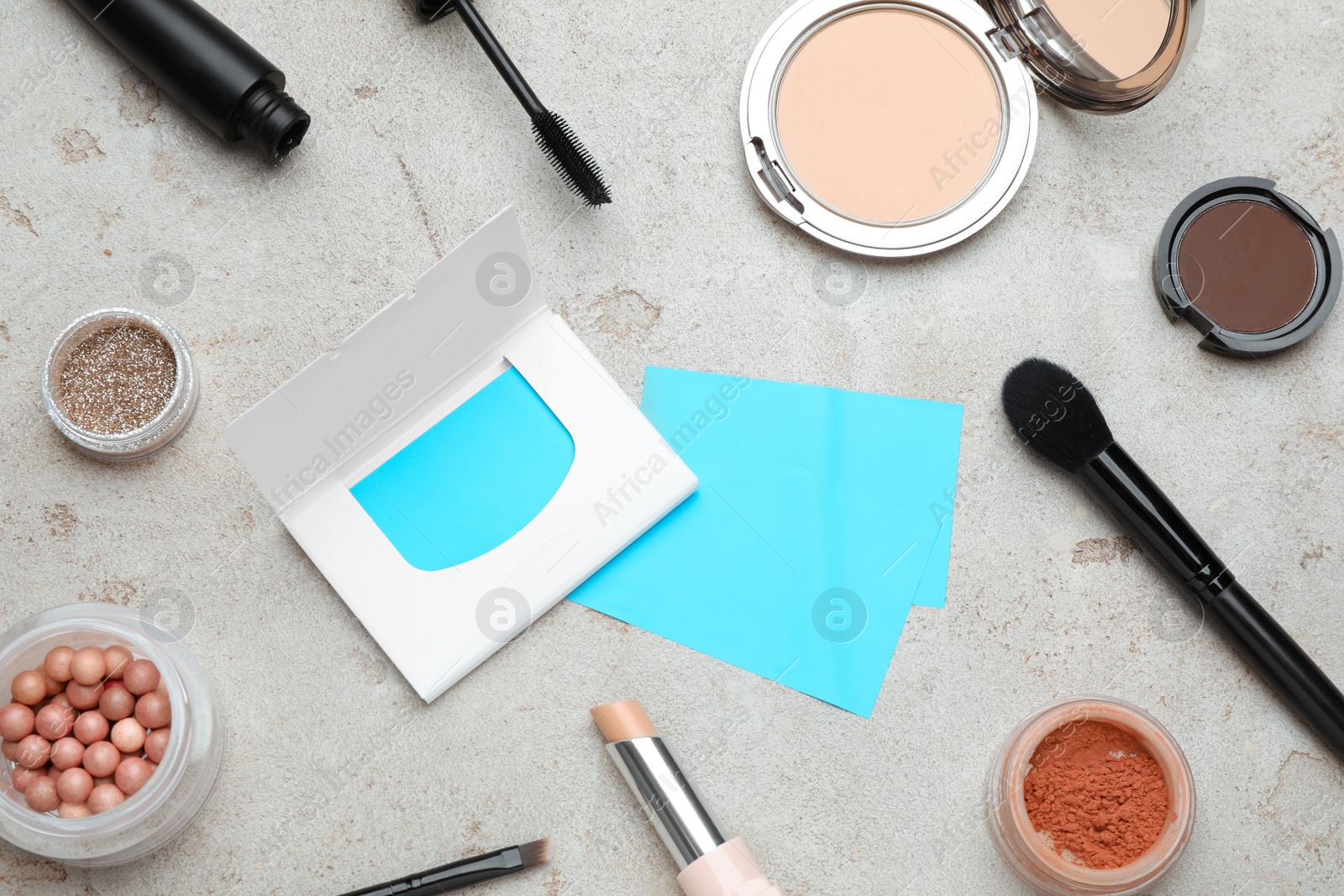 Photo of Facial oil blotting tissues and different decorative cosmetics on light grey background, flat lay. Mattifying wipes