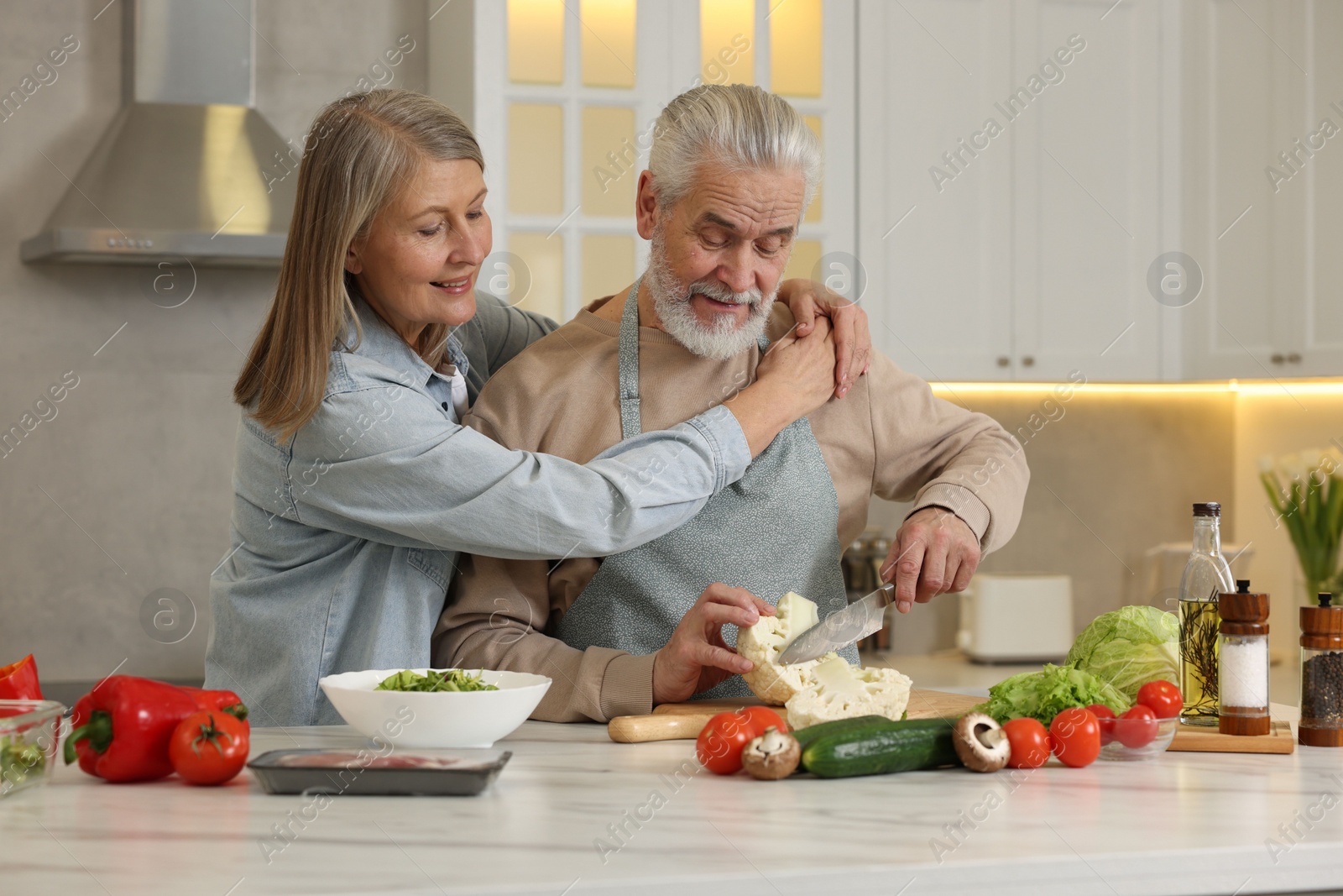 Photo of Happy senior couple cooking together in kitchen