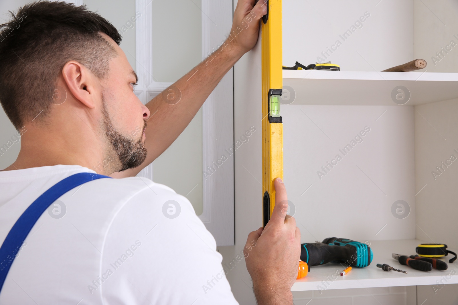 Photo of Worker measuring newly installed kitchen furniture indoors