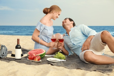 Photo of Beautiful young couple having picnic at sea beach