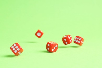 Photo of Many red game dices falling on green background