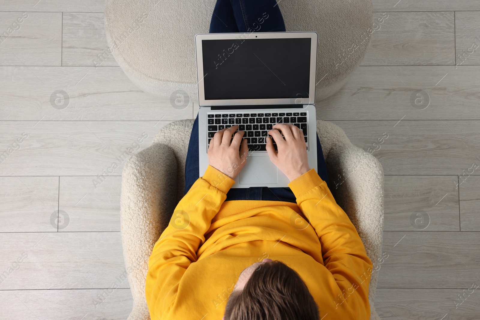 Photo of Man working with laptop in armchair, top view