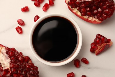 Bowl of pomegranate sauce and fresh ripe fruit on white marble table, flat lay