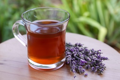 Photo of Beautiful lavender flowers and cup of aromatic tea on wooden table, closeup