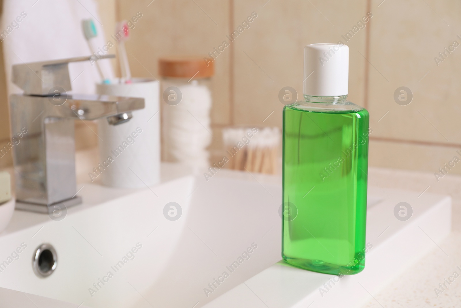 Photo of Fresh mouthwash in bottle on sink in bathroom, closeup