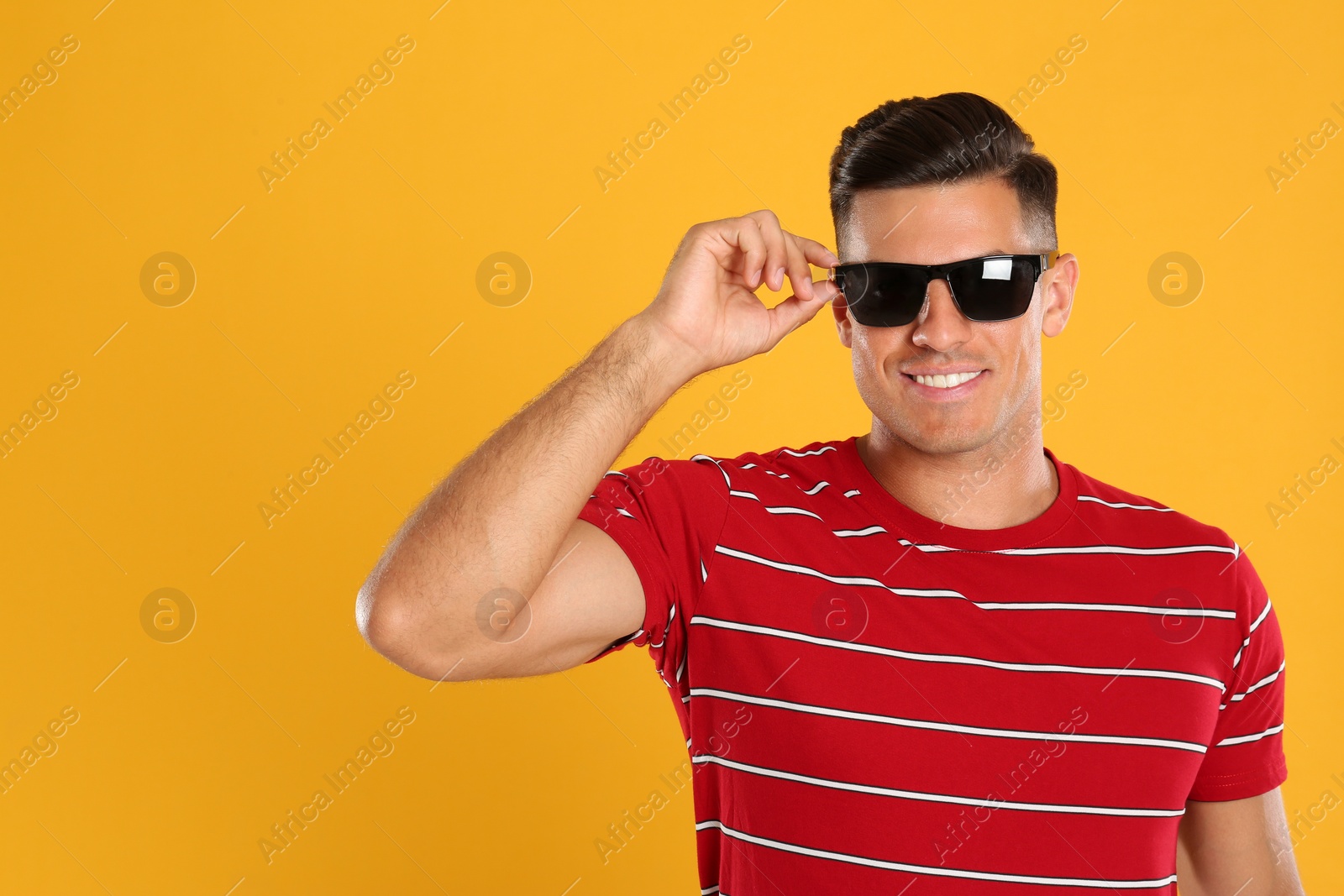 Photo of Handsome man wearing sunglasses on yellow background