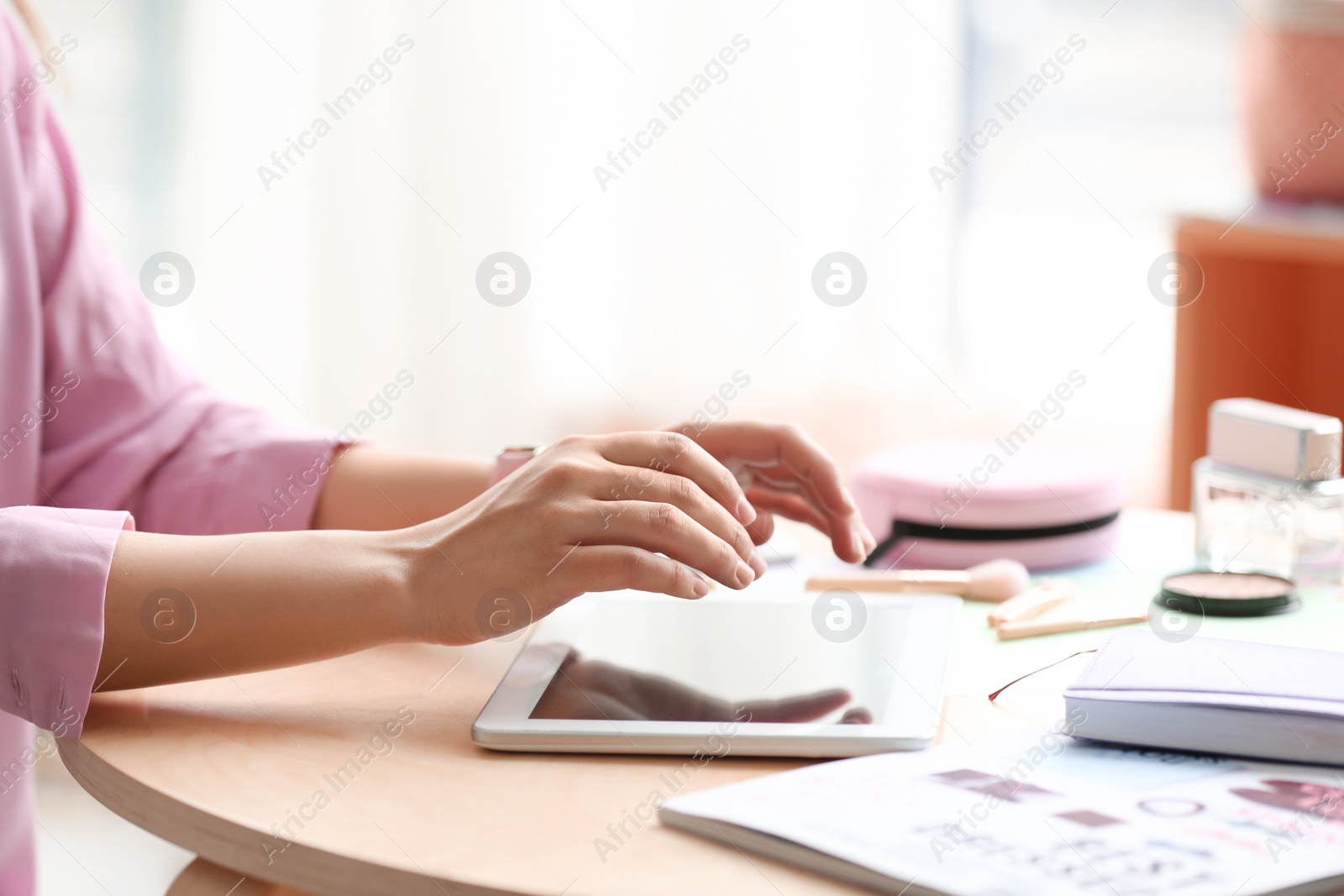 Photo of Female blogger using tablet at table indoors