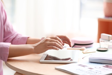 Photo of Female blogger using tablet at table indoors