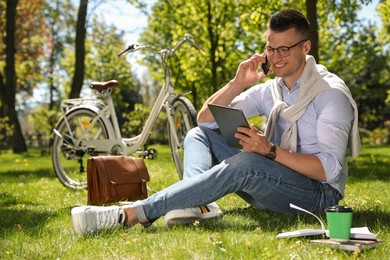 Photo of Man working with tablet on grass in park