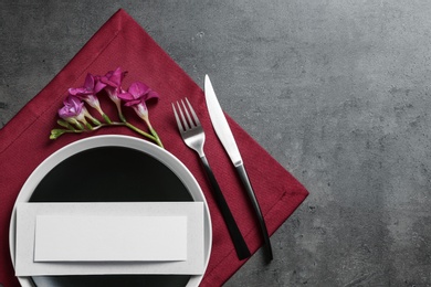 Photo of Stylish elegant table setting and blank card on color background, top view. Space for text