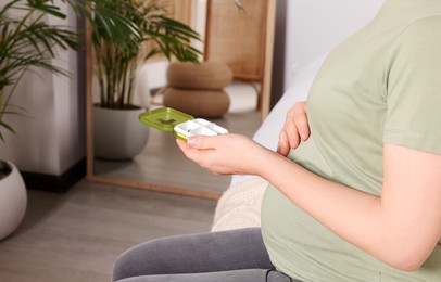 Photo of Pregnant woman taking pills at home, closeup. Space for text