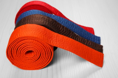 Photo of Colorful karate belts on wooden background, closeup