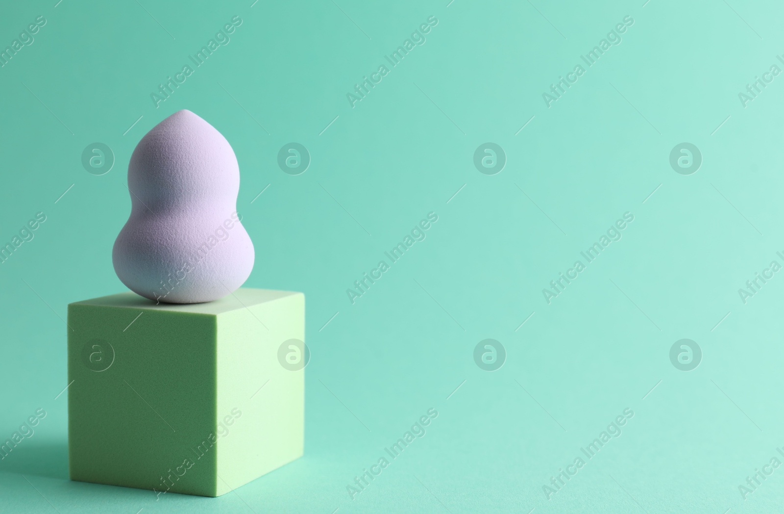 Photo of Stylish presentation of makeup sponge on turquoise background, space for text